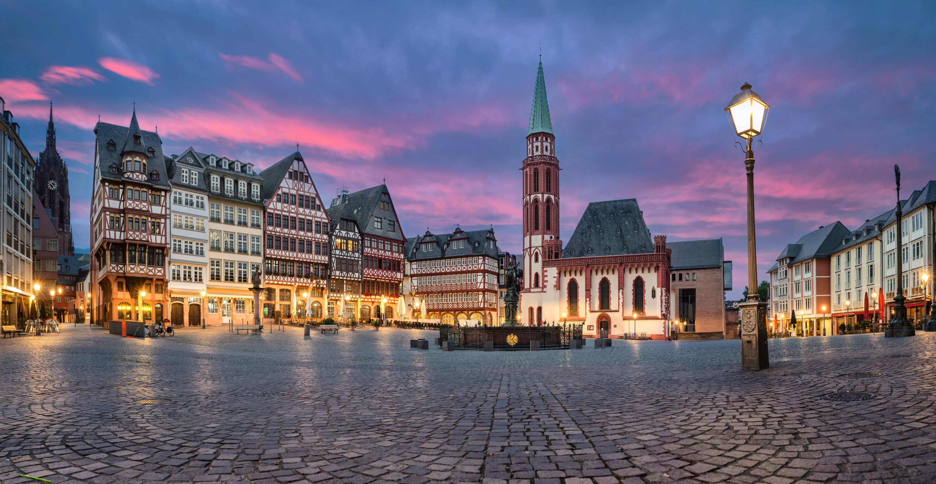 A cobblestone square with historic half-timbered buildings and a prominent church tower.