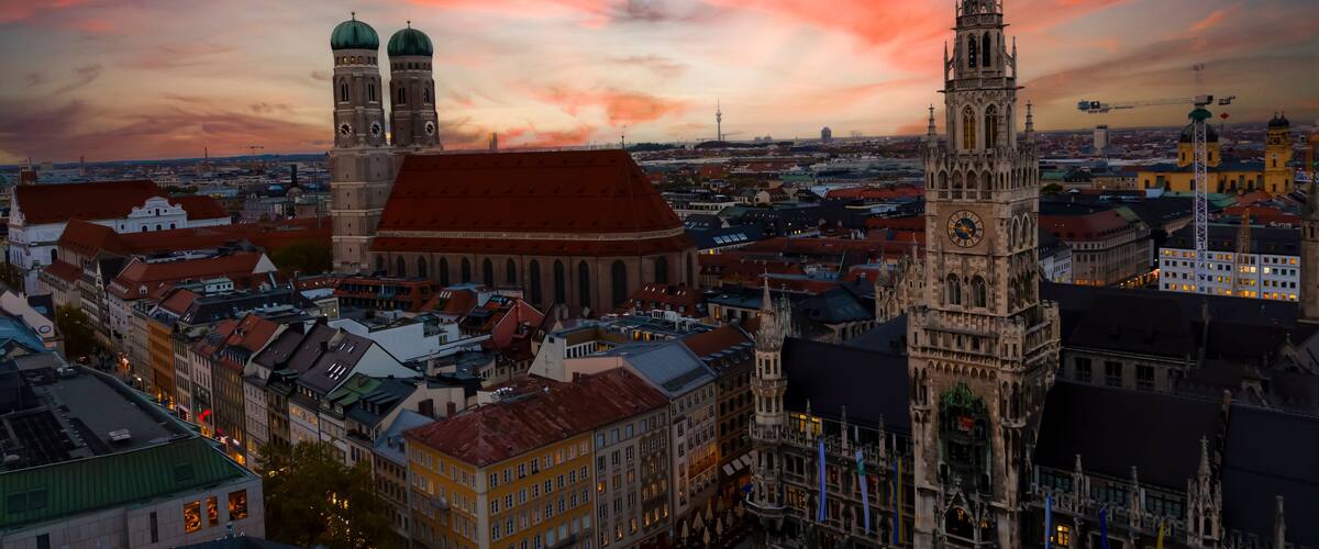 A cityscape with prominent towers and a cathedral at sunset.