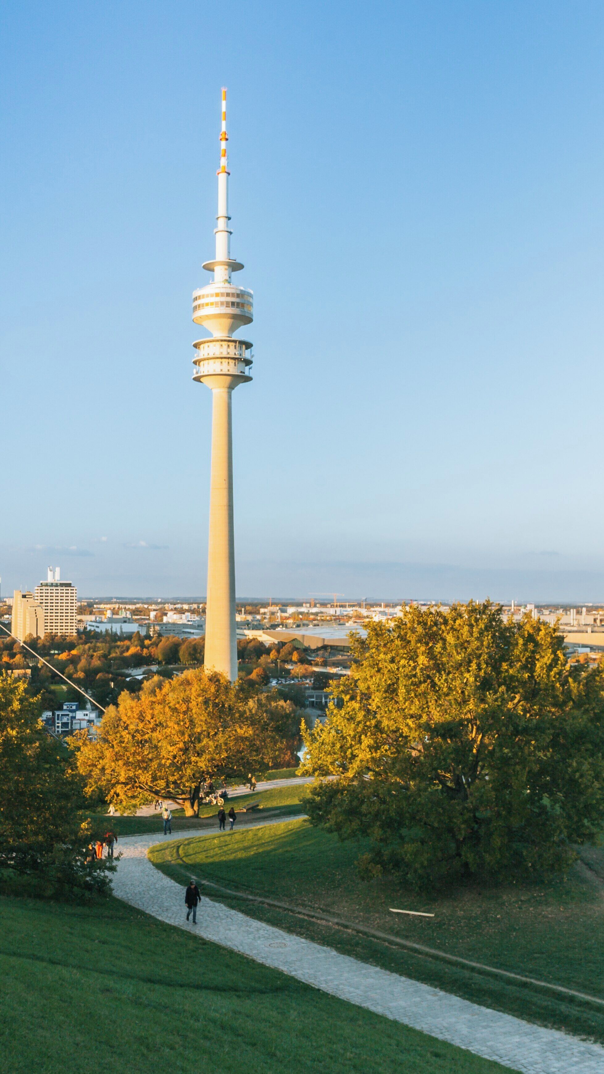 Tower overlooking Olympic Park in Munich, showcasing vibrant autumn foliage and clear blue skies during a sunny afternoon