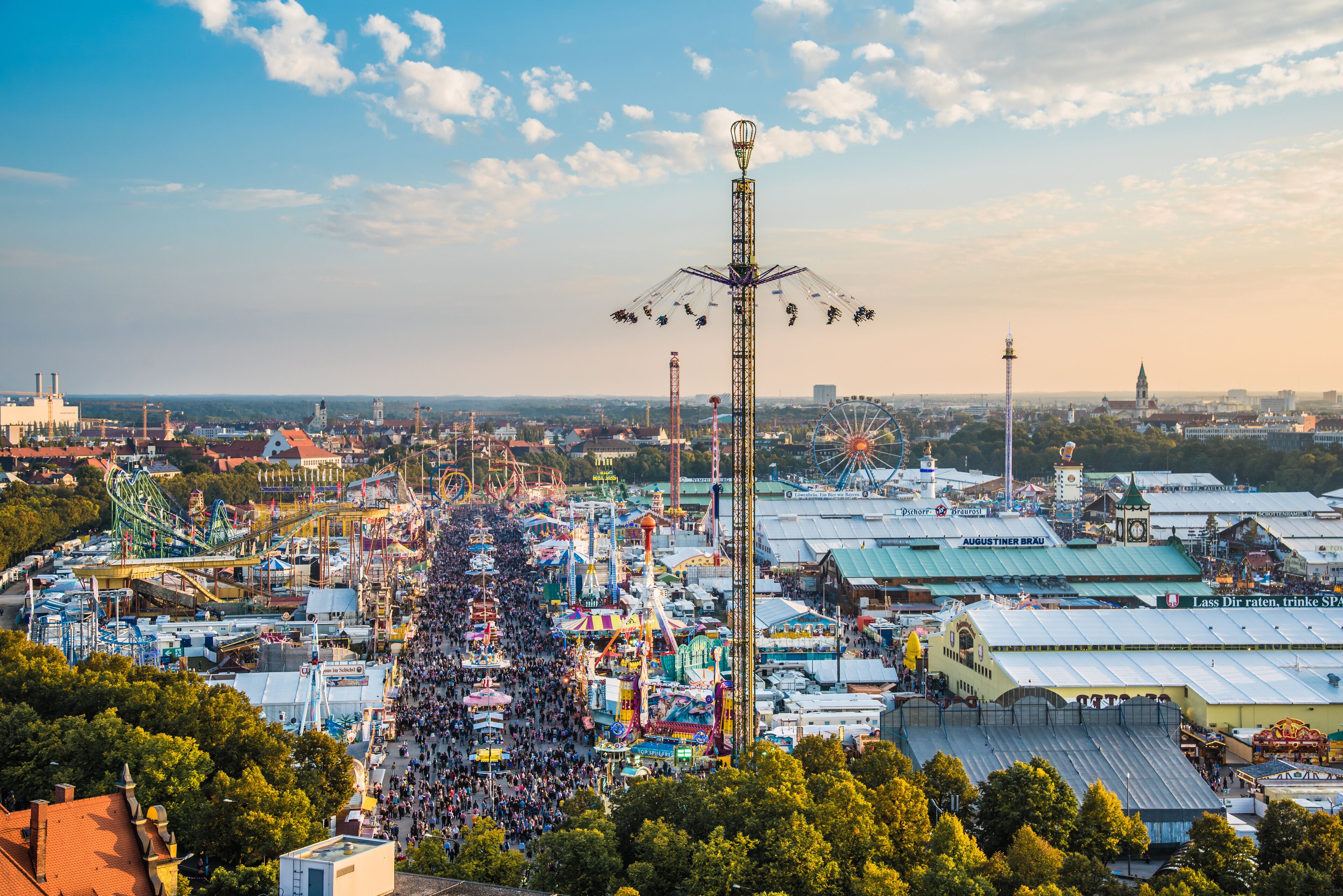 A bustling fairground with a Ferris wheel, amusement rides, and a tall observation tower.