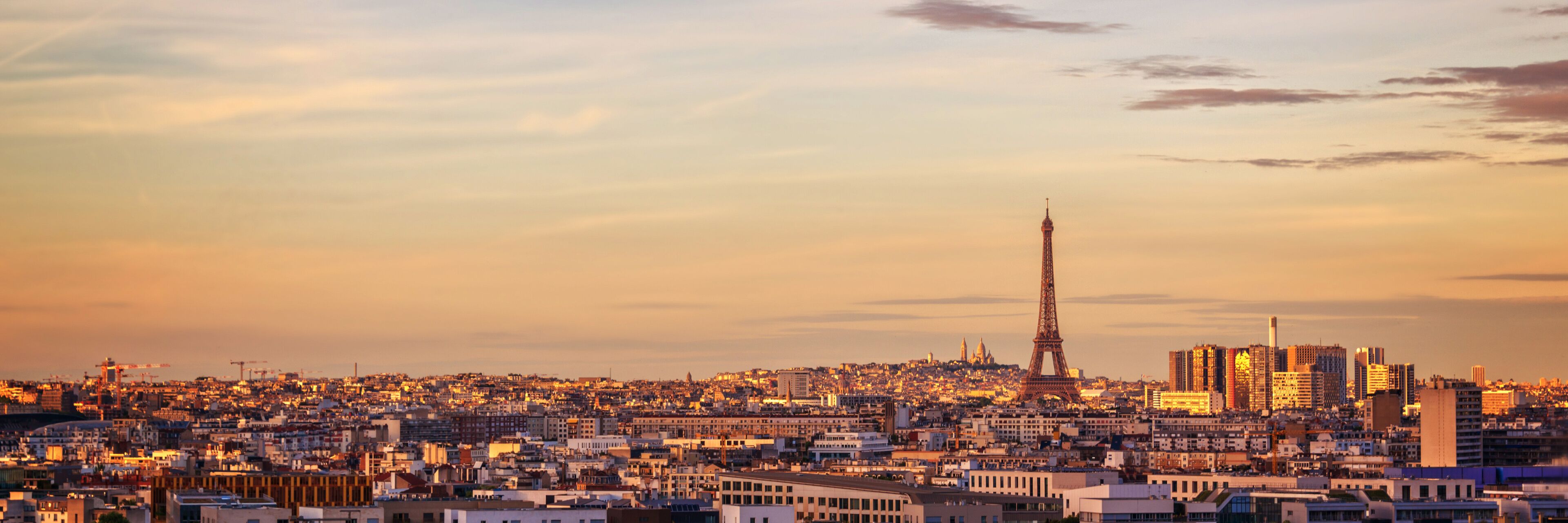 A cityscape with the Eiffel Tower and modern buildings at sunset.