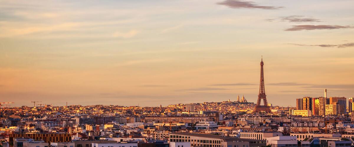 A cityscape with the Eiffel Tower and modern buildings at sunset.