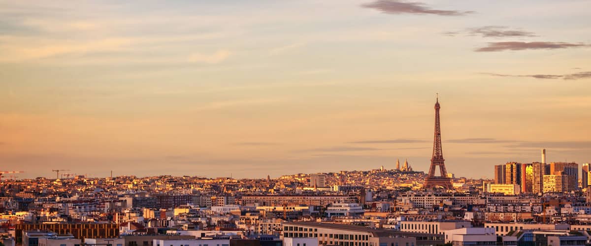 A cityscape with the Eiffel Tower and modern buildings at sunset.