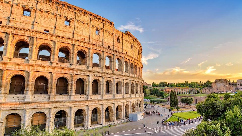 The Colosseum in Rome with its arches and surrounding gardens.