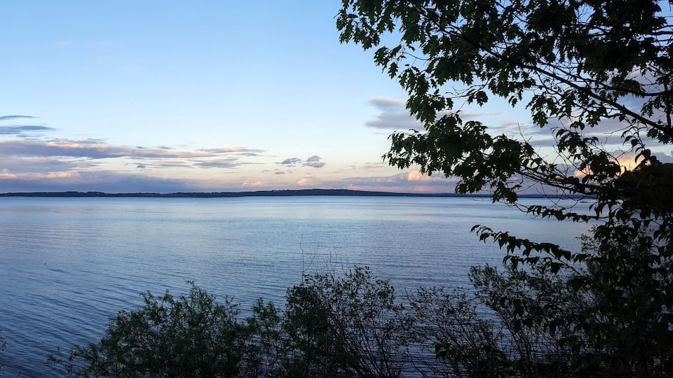 A calm lake with a clear sky and distant landforms.