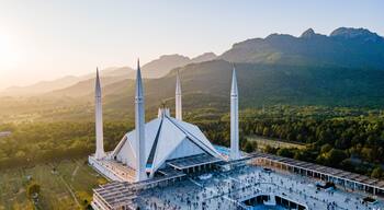 A mosque with four minarets and a large courtyard surrounded by mountains.
