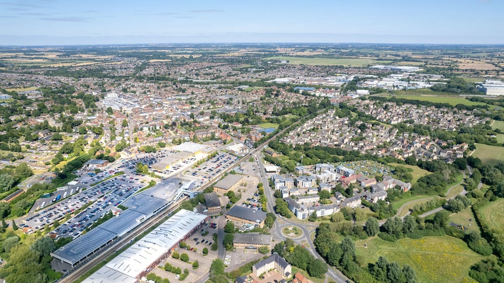 Vue aérienne d’une ville comprenant une vaste zone industrielle, des quartiers résidentiels et des champs verdoyants environnants.