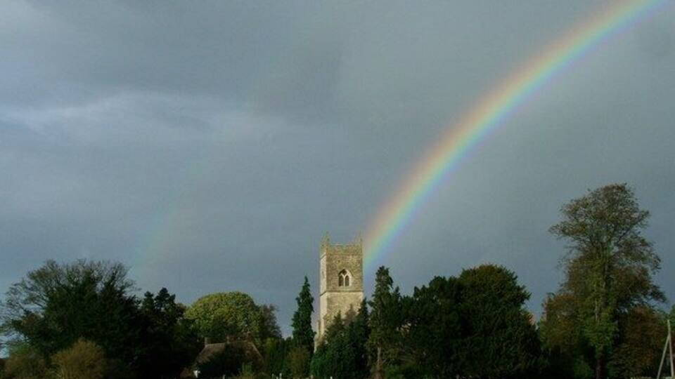 A church tower with a rainbow in the background.