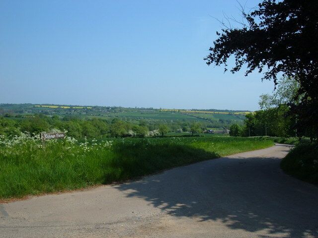 A rural road curving through a green landscape with a sign reading "Grosse Farm."