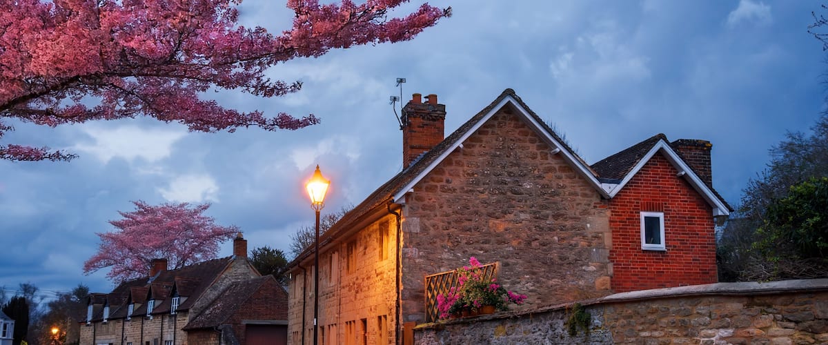 A stone building with a red brick section, a street lamp, and cherry blossoms.