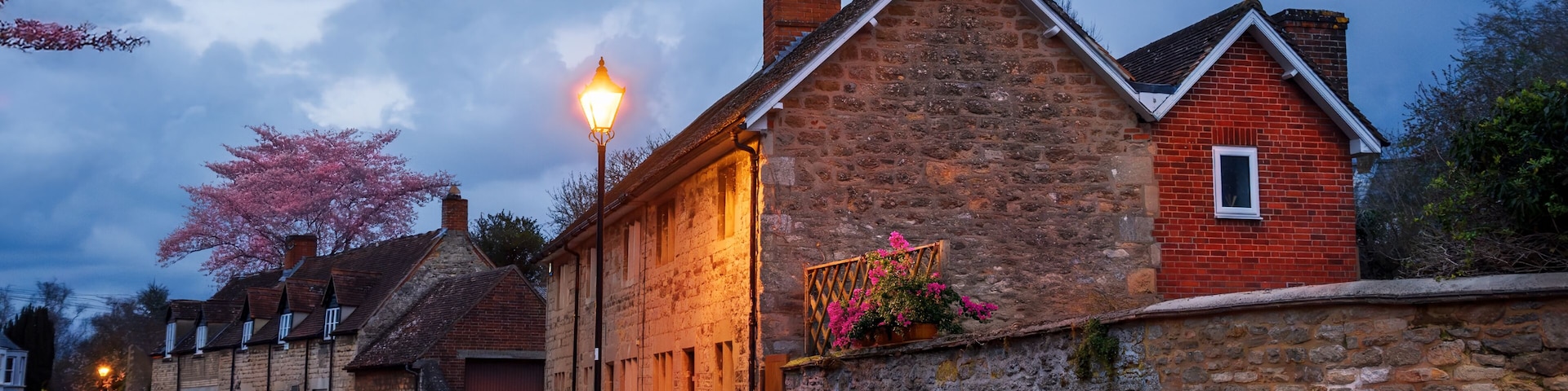 A stone building with a red brick section, a street lamp, and cherry blossoms.