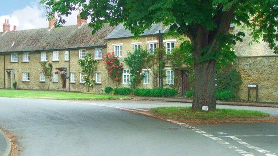 A row of stone houses with a tree in the foreground.