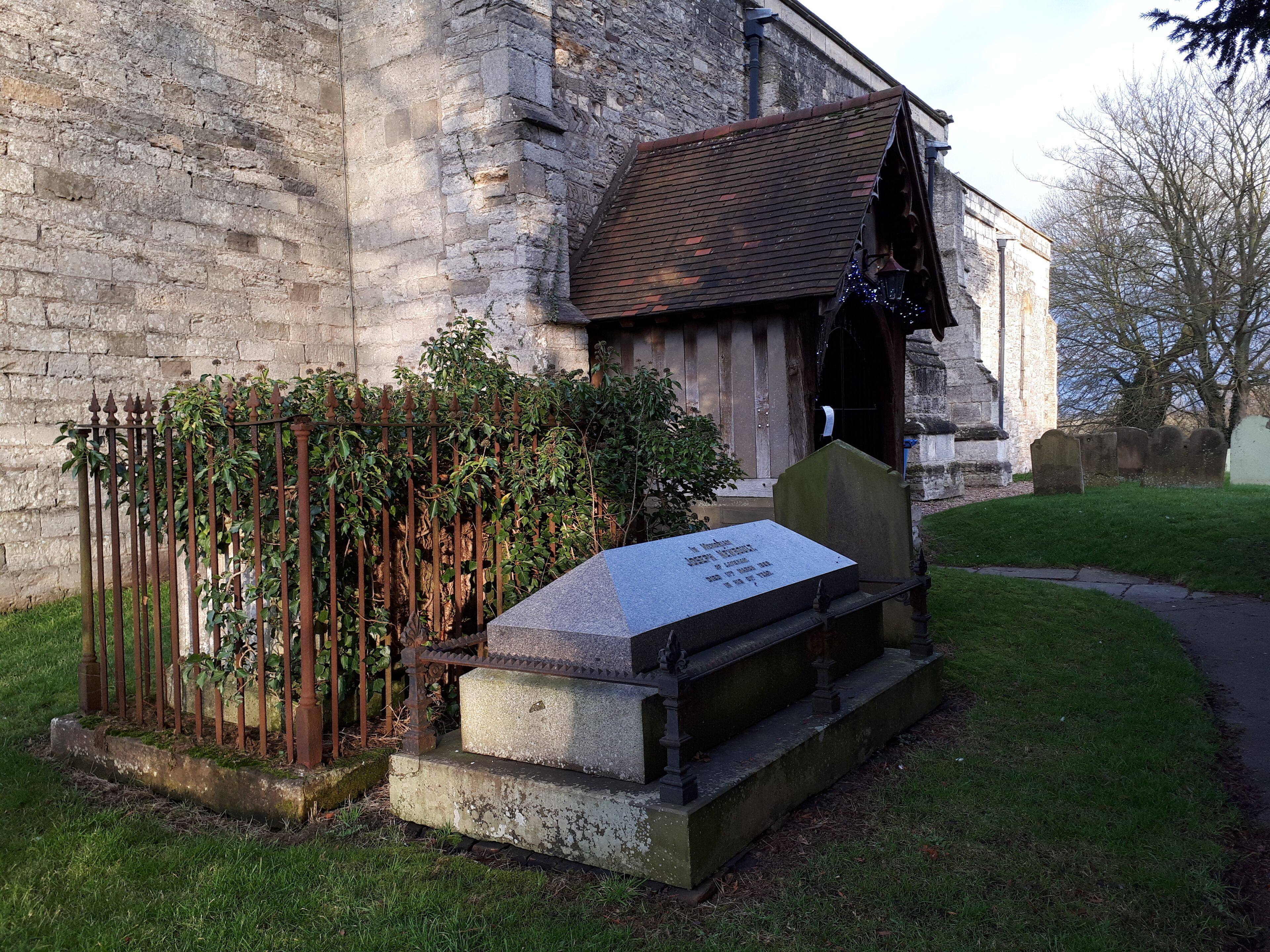 A stone church with a grave marker in front.