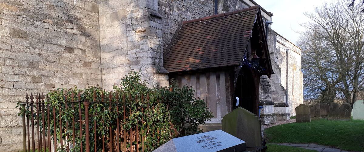 A stone church with a grave marker in front.