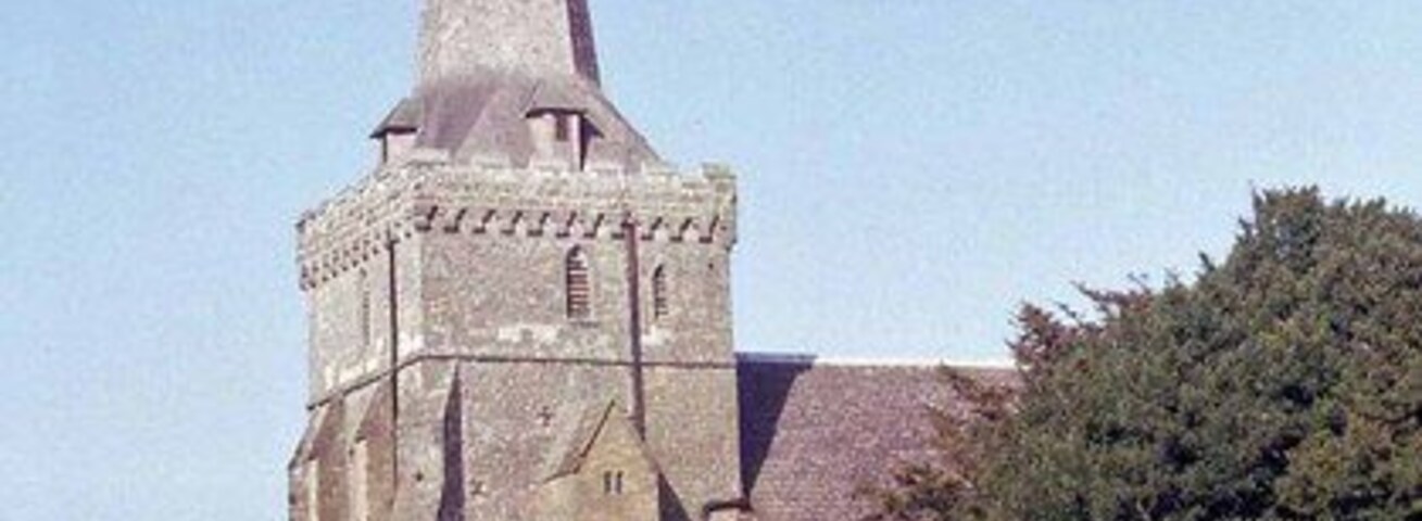 Una iglesia con una aguja alta, rodeada por un cementerio con numerosas lápidas.