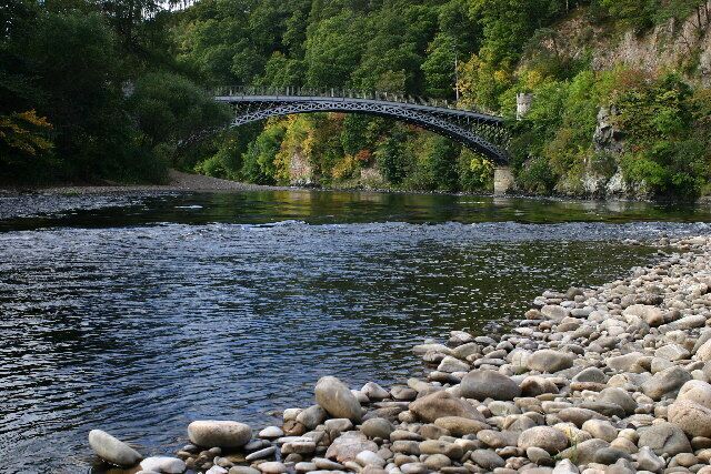A stone bridge over a river, surrounded by rocks and greenery.