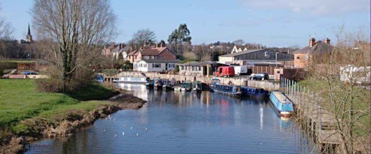 A river with boats, houses, and a church in the background.