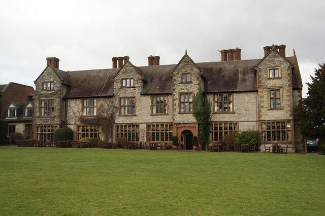 A large stone building with multiple windows and a grassy lawn in front.