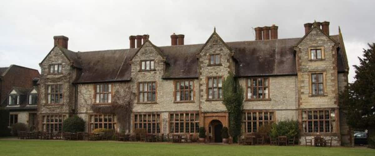 A large stone building with multiple windows and a grassy lawn in front.