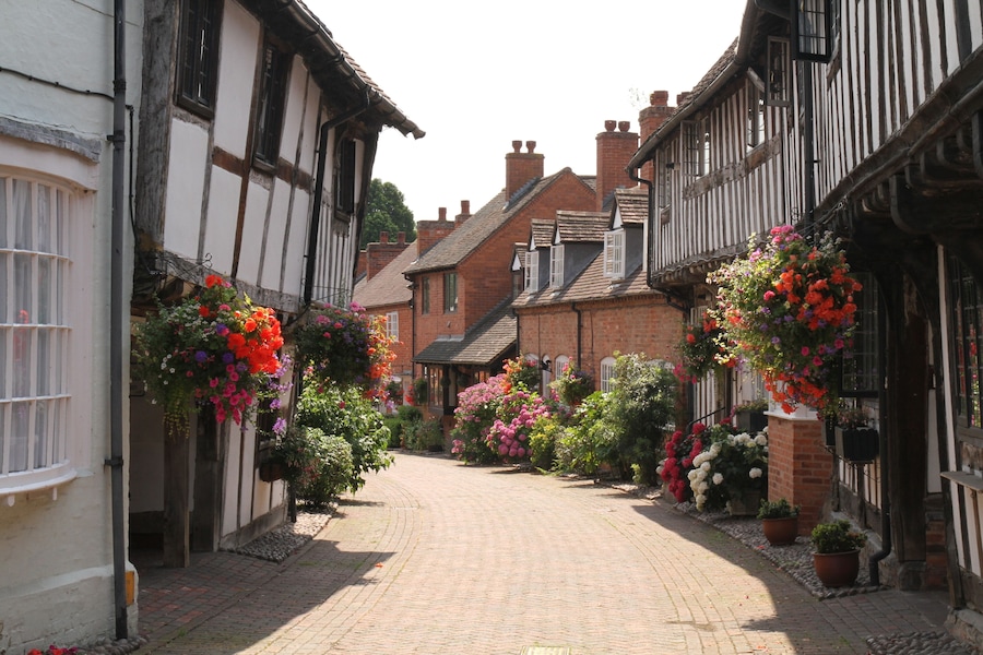 Half Timbered, Black & White Houses in Shakespeare's Country Malt Mill Lane Alcester Warwickshire, UK. Hanging baskets & floral blooms in High Summer.