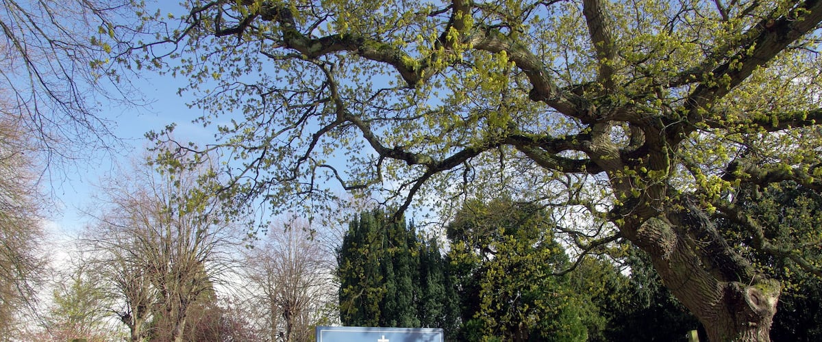 A cemetery with a sign for The Parish Church of St. Laurence.