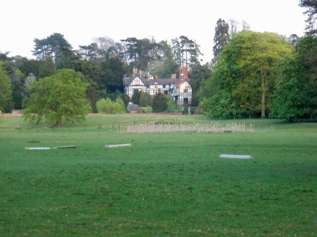 A grassy field with a large house in the background.