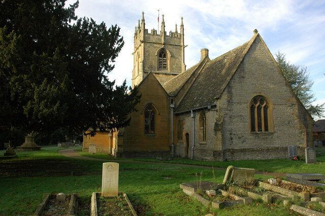 A church with a tall tower and a large tree in the foreground.