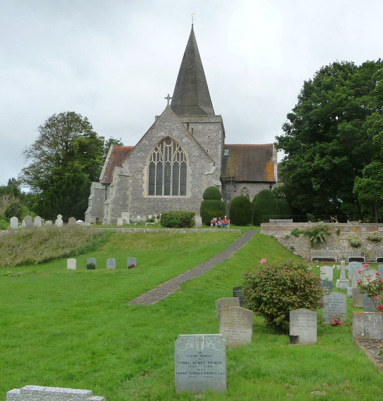 A church with a tall spire, a graveyard with headstones, and a pathway leading to the church.