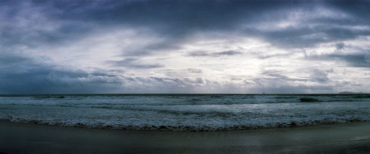 A beach with waves and a cloudy sky.