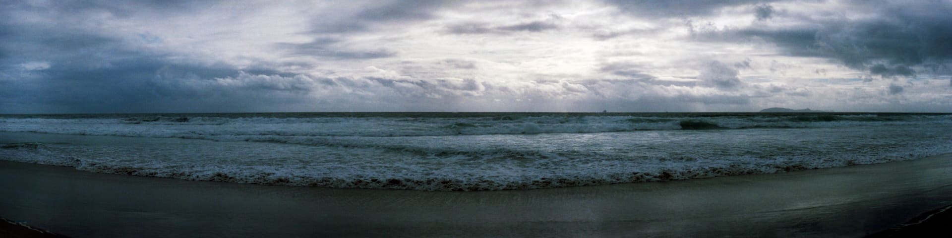 A beach with waves and a cloudy sky.
