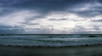 A beach with waves and a cloudy sky.