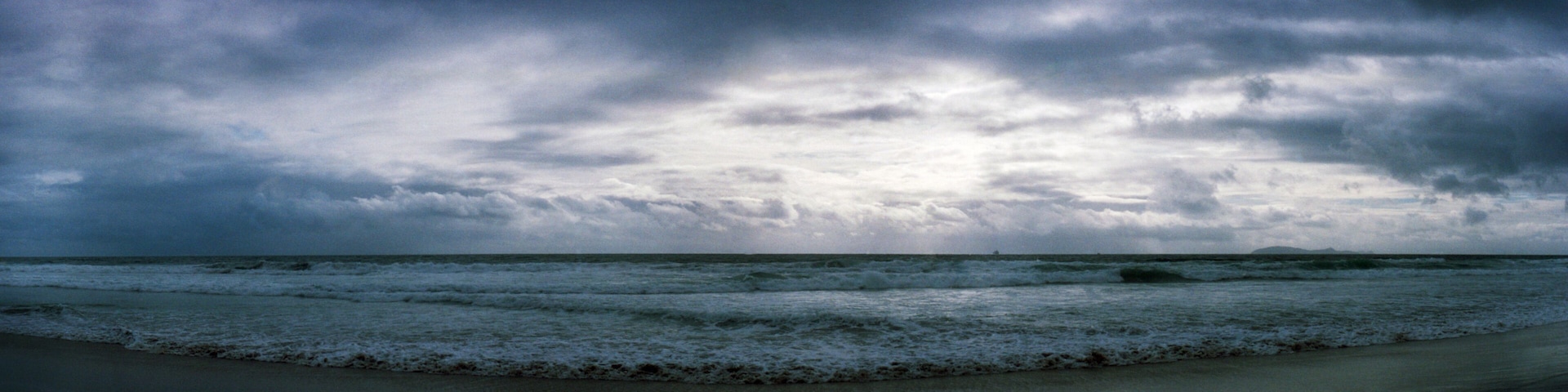A beach with waves and a cloudy sky.