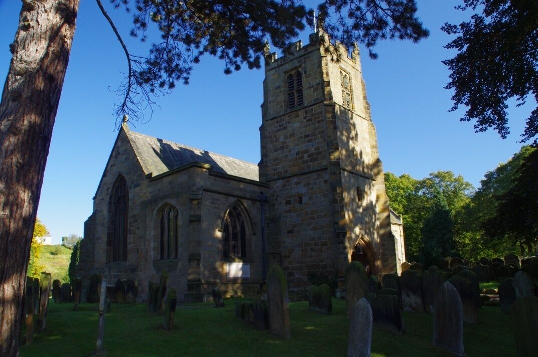 A historic church with a tall tower and a graveyard.