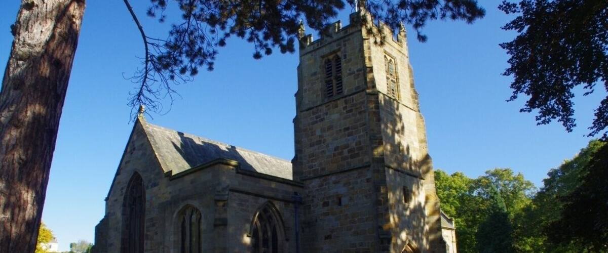 A historic church with a tall tower and a graveyard.