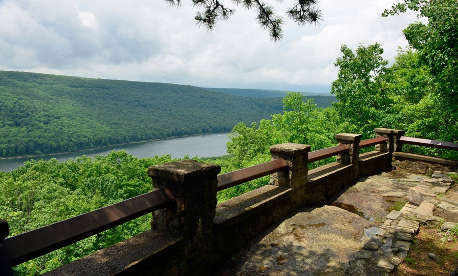 A stone viewing platform overlooking a lake surrounded by dense forest.