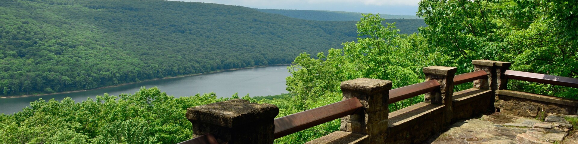 Uma plataforma de pedra com vista para um lago rodeado por floresta densa.