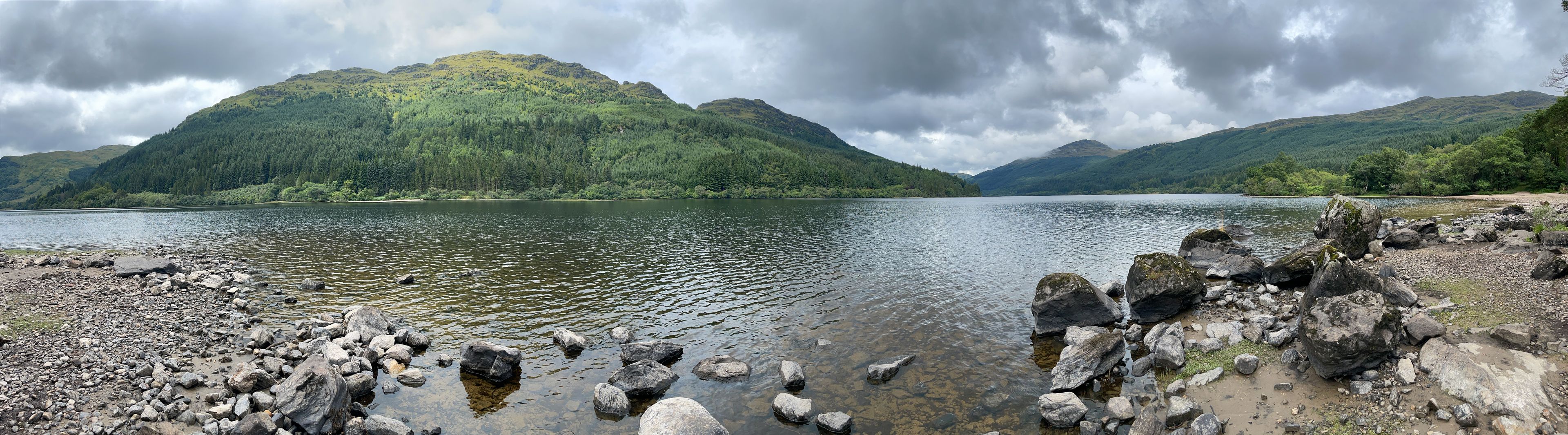 Ein See, umgeben von Bergen mit einer felsigen Uferlinie.