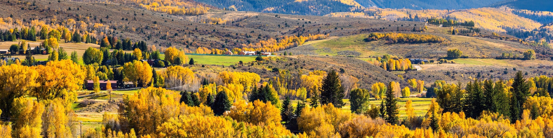 A mountainous landscape with autumn foliage, a small village, and a river.