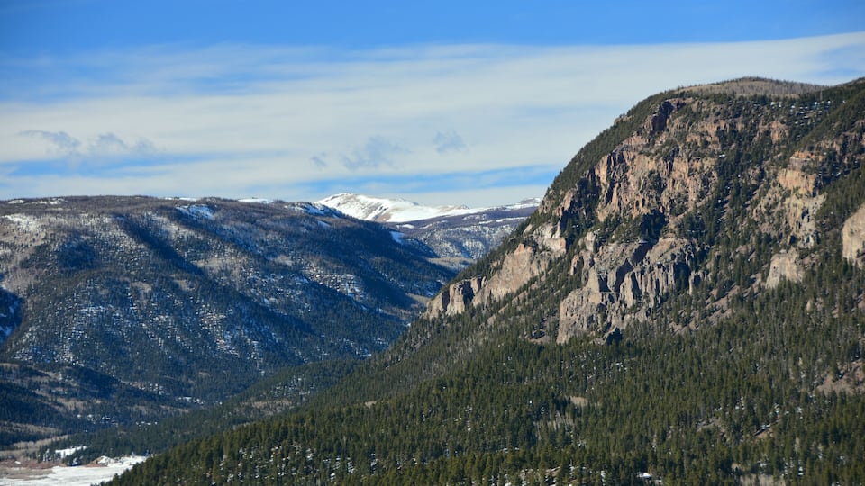 A mountainous landscape with snow-capped peaks and dense forests.
