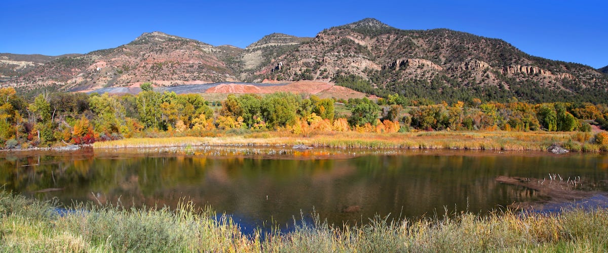A lake surrounded by autumn-colored trees and mountains.