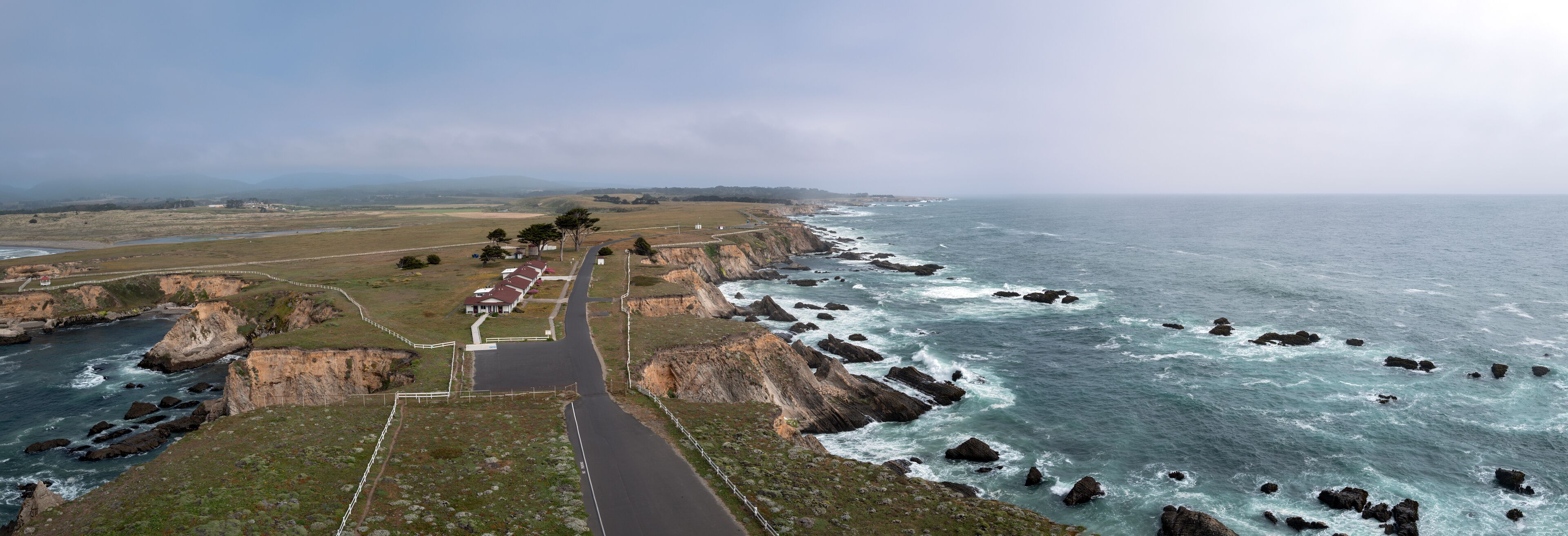 A coastal road with rocky cliffs and ocean waves.