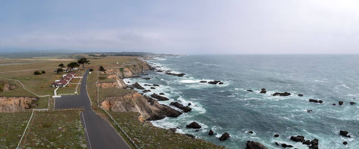 A coastal road with rocky cliffs and ocean waves.