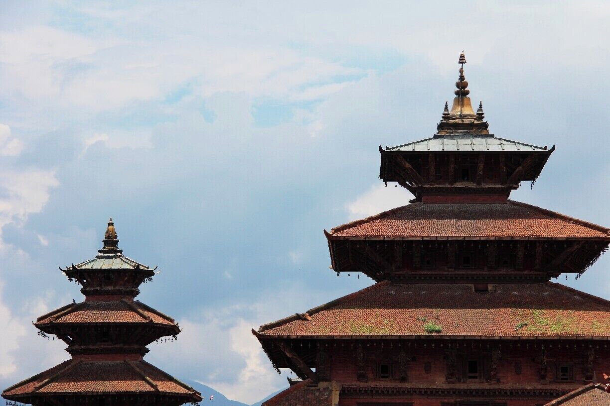 A traditional multi-tiered temple with a golden spire, set against a cloudy sky.