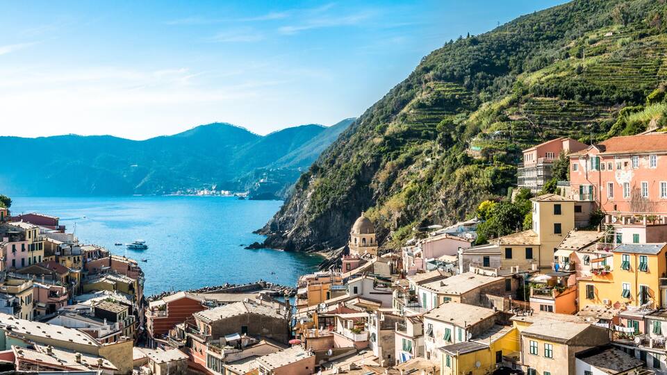A coastal village with terraced houses, a church, and a sea view.