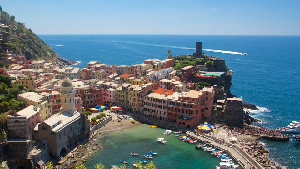 A coastal town with colorful buildings, a rocky coastline, and boats docked at the harbor.
