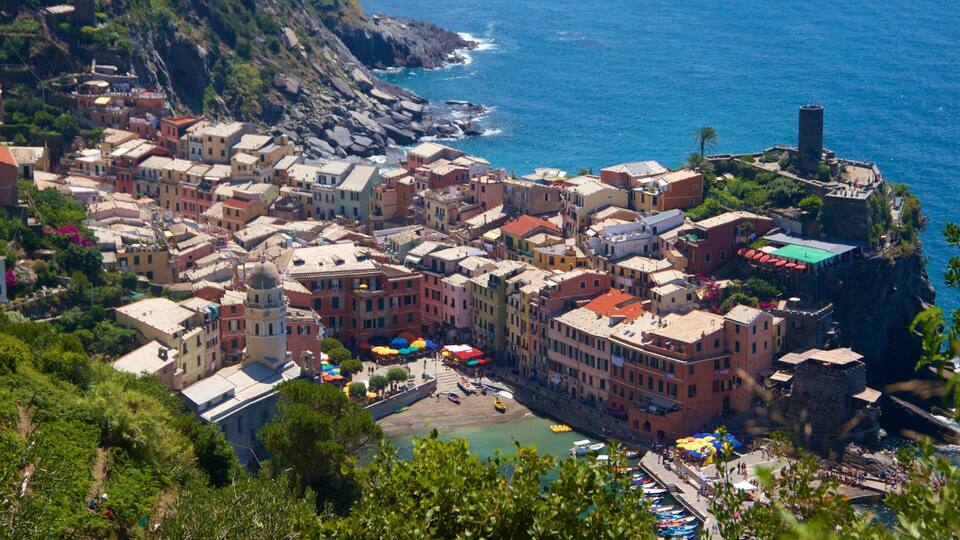 A coastal town with colorful buildings, a rocky coastline, and a historic tower.