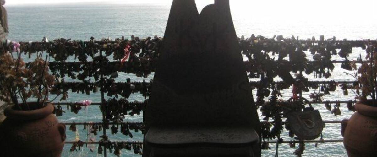A bench with a heart-shaped cutout, overlooking the sea.