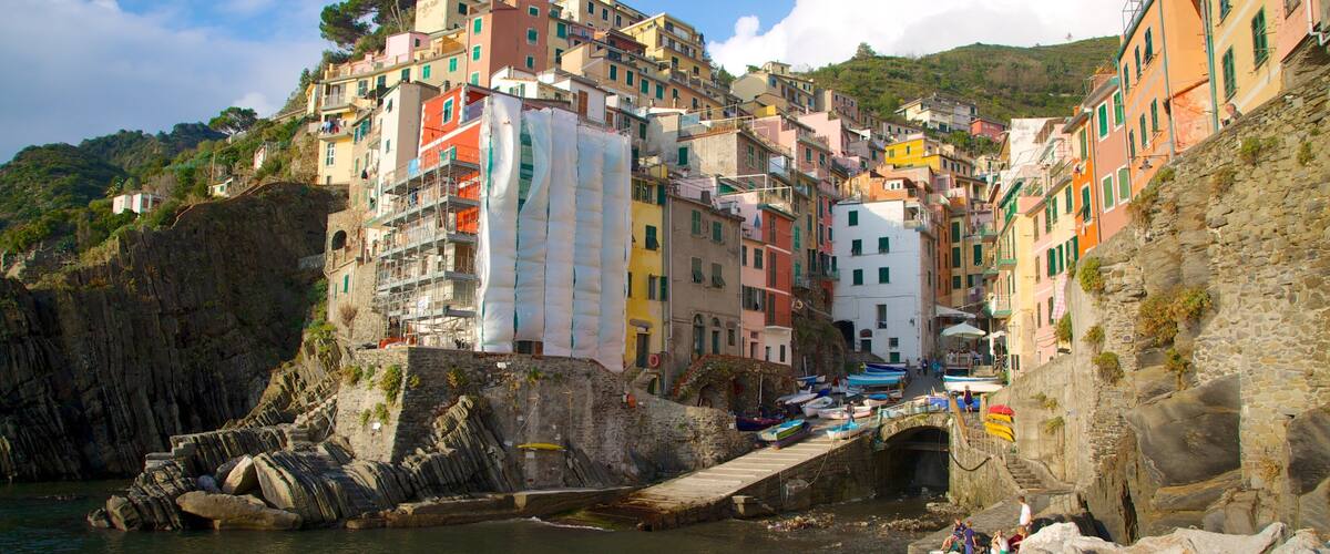 A coastal town with colorful buildings, a rocky shoreline, and a small bridge.