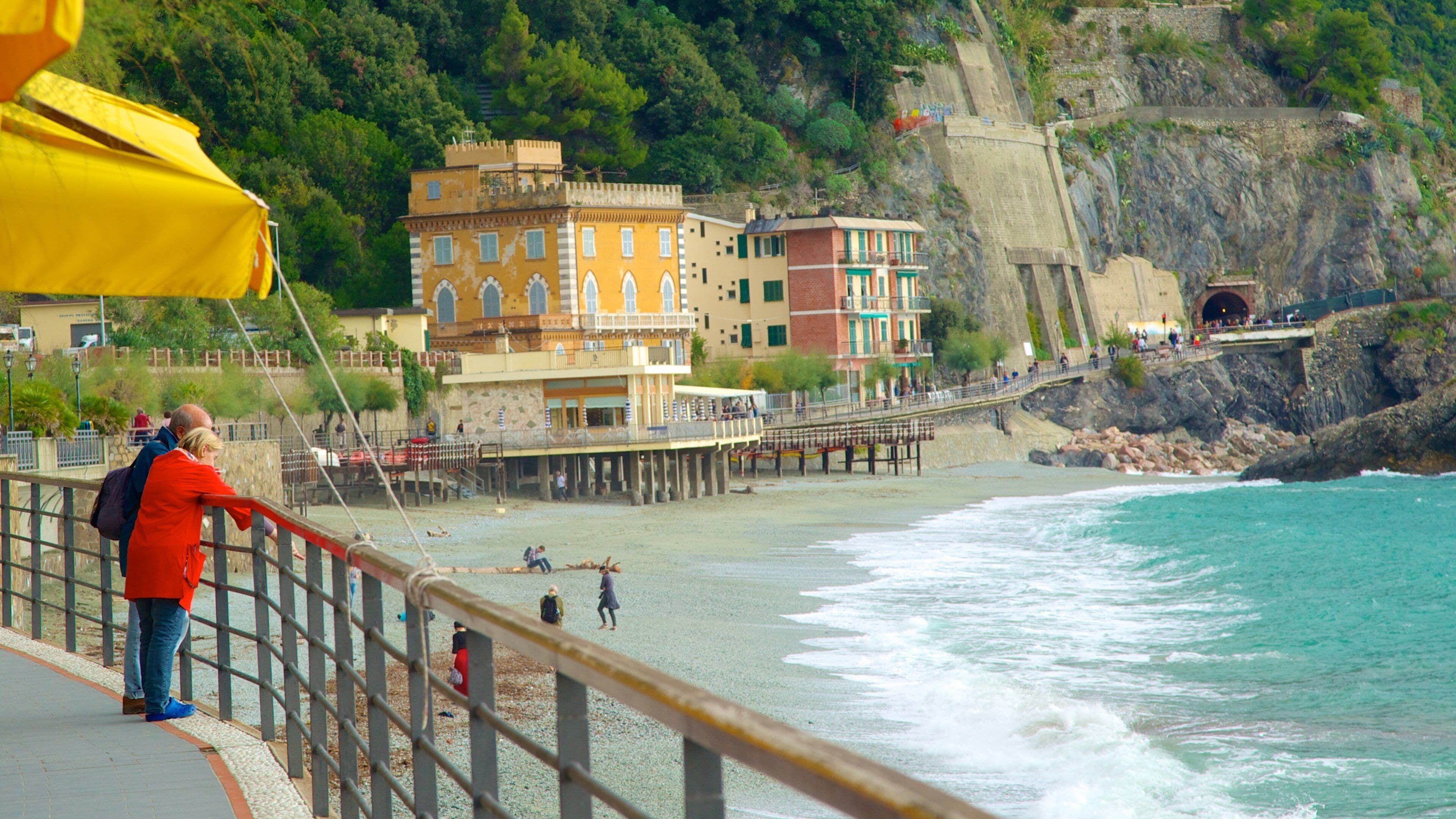 A coastal town with colorful buildings, a rocky cliff, and a pier extending into the sea.