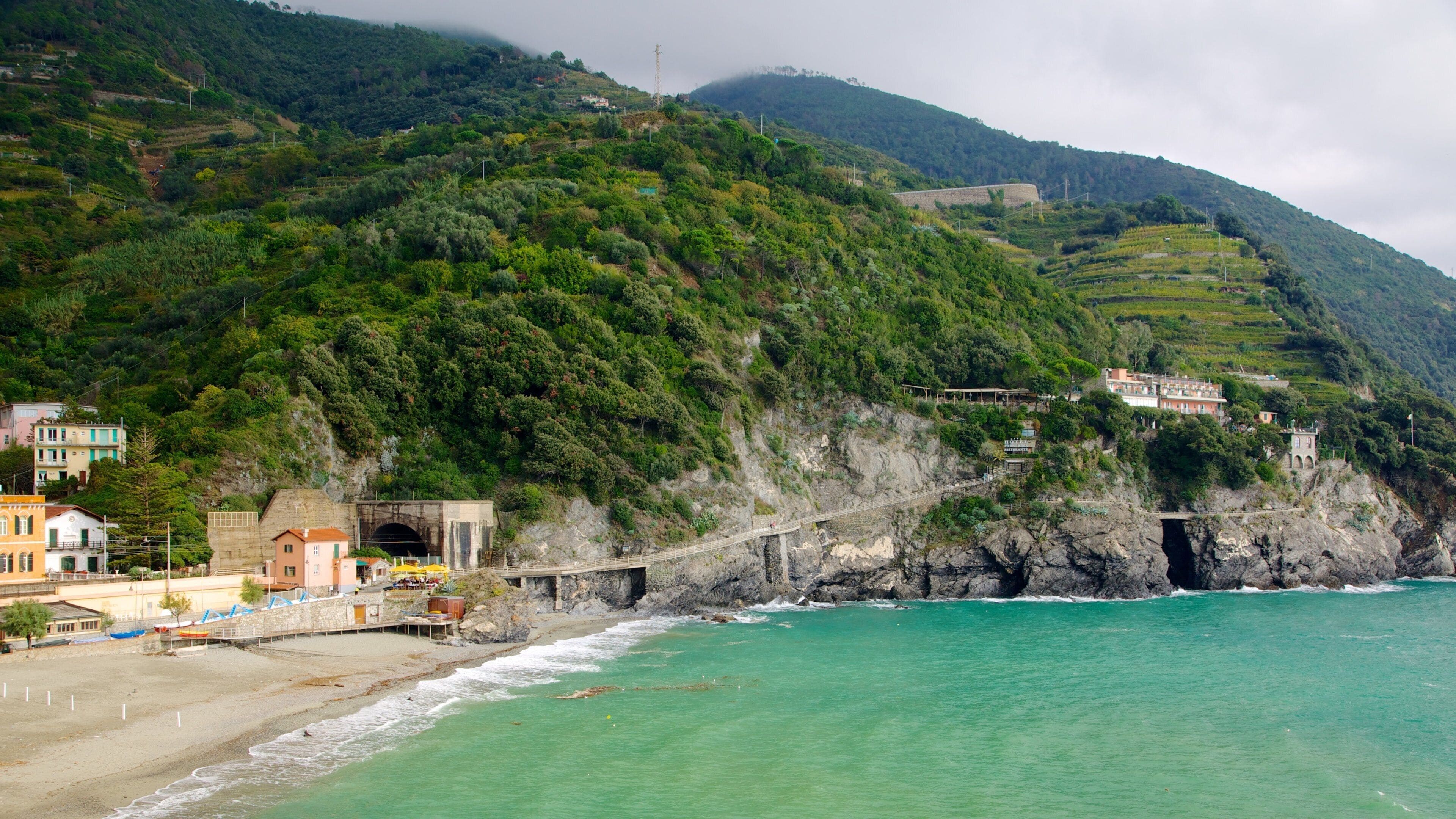 A coastal town with a beach, a bridge, and a mountain backdrop.